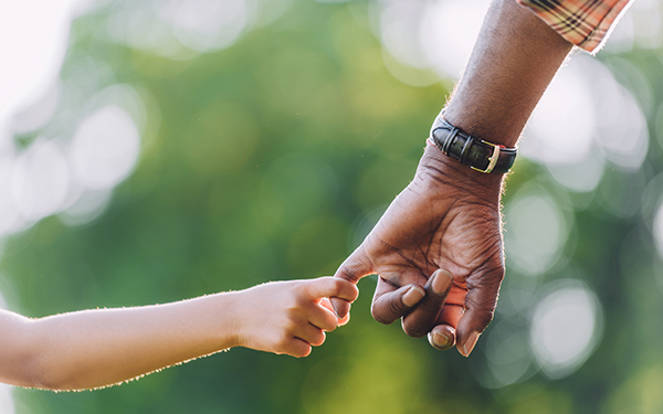 child holding the pinky finger of a man