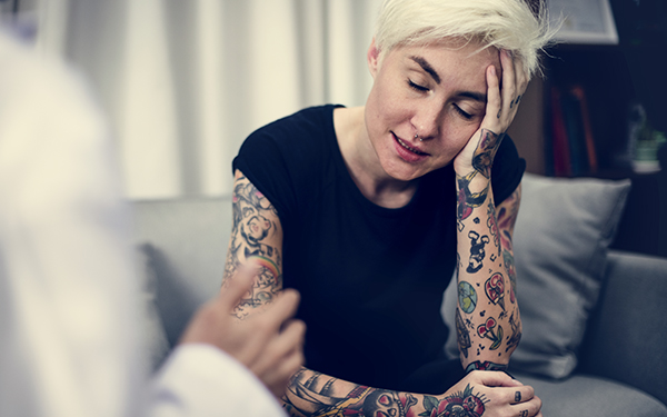 tattooed woman upset and talking with a counseler 